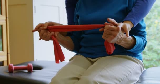 Средняя Часть Физиотерапевта Корректирует Позицию Пожилой Женщины Клинике — стоковое видео