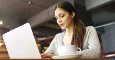 4 k kafede dizüstü bilgisayar kullanan genç kadın