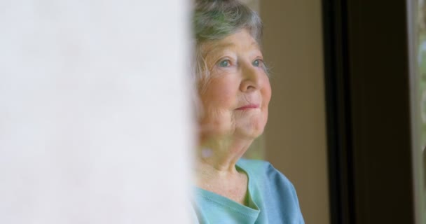 の自宅の窓から見ている年配の女性 — ストック動画