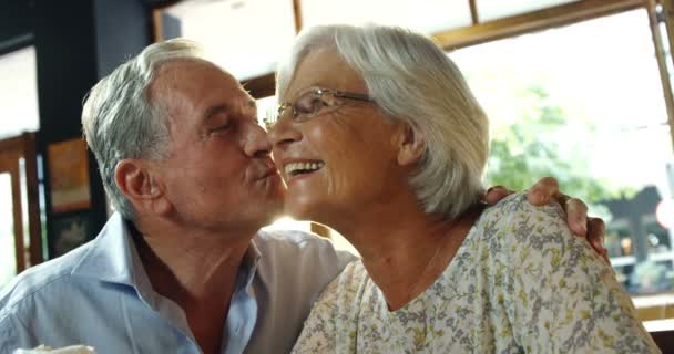 年配の男性が明るい日光 に対してカフェで年配の女性にキス — ストック動画