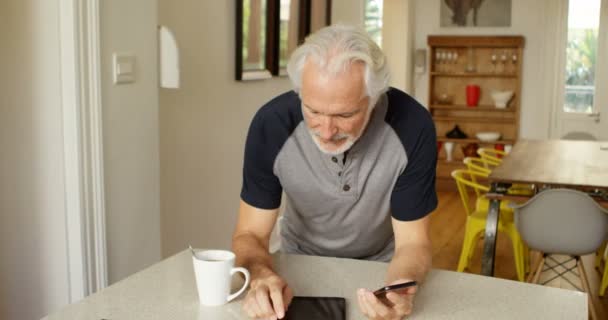 年配の男性がホームの でテーブルの上の携帯電話を使用して — ストック動画