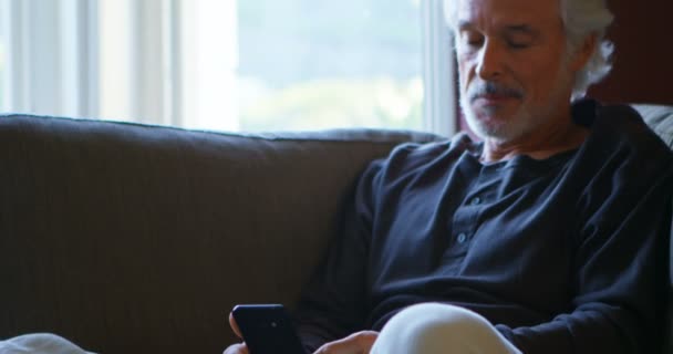 Ανώτερος Άνθρωπος Χρησιμοποιεί Κινητό Τηλέφωνο Στον Καναπέ Στο Σπίτι — Αρχείο Βίντεο