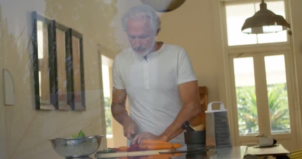 Старший Чоловік Нарізає Овочі Кухні Вдома — стокове відео