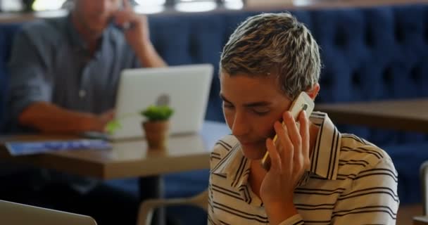 Mujer Hablando Teléfono Móvil Mientras Que Hombre Usando Ordenador Portátil — Vídeos de Stock