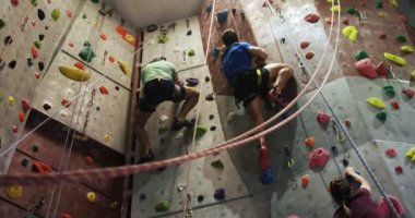 Erkek ve kadın bouldering spor salonu 4 k yapay bir duvara tırmanma düşük açılı görünüş