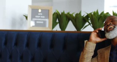 Kanepede oturan ve telefonda 4 k 4 k alarak üst düzey iş adamı gülümseyen