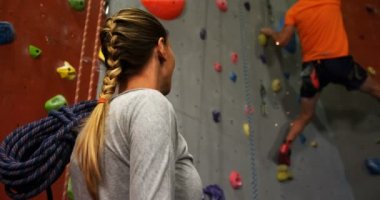 4 k bouldering salonunda yapay duvar tırmanışı bir adam izliyor kadın