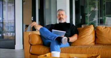 Düşünceli executive Office 4 k kanepede dizüstü bilgisayar kullanarak