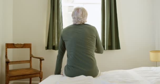 の自宅の寝室でベッドに座っている年配の男性の後姿 — ストック動画
