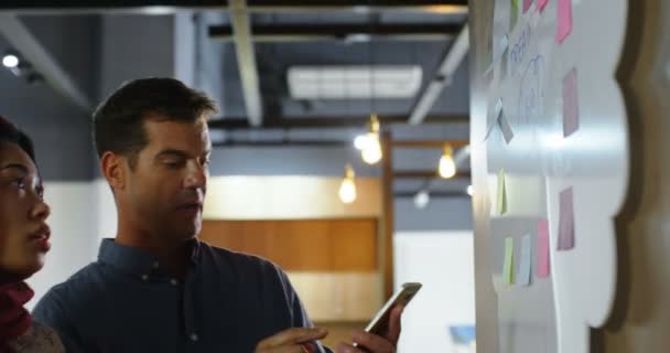 Ejecutivos Discutiendo Sobre Nota Adhesiva Pared Oficina — Vídeos de Stock