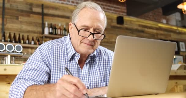 Senior Schreibt Auf Während Laptop Restaurant Verwendet — Stockvideo