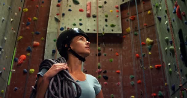 ボルダリング で人工壁で見て回ってロープを持つ女性 — ストック動画