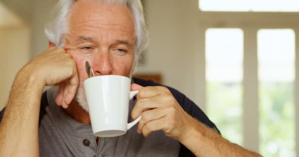 のテーブルにコーヒーを持って思いやりのある年配の男性 — ストック動画