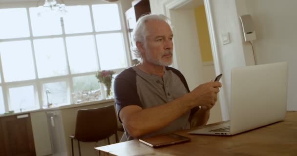 Senior Man Praten Mobiele Telefoon Zitten Aan Tafel Huis — Stockvideo