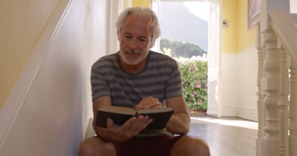 親切な年配の男性ホーム で本を読んで — ストック動画
