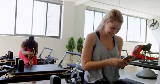 Leende Kvinna Med Mobiltelefon Fitnesstudion — Stockvideo