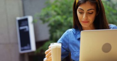 Genç kadının milkshake açık kafe 4 k laptop kullanırken sahip