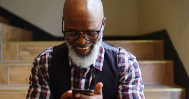 Merdiven üzerinde oturan ve bir metin yazarak komuta sizde gülümseyen telefonda 4k 4k mesaj