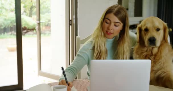 の彼女の犬を自宅でメモ帳に書く若い女性 — ストック動画