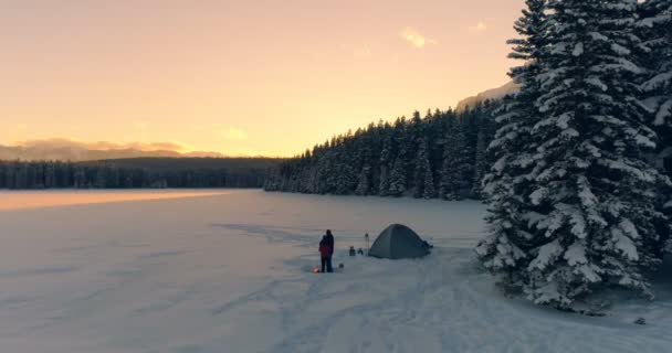 两个游客在帐篷附近积雪覆盖的景观在日落4K — 图库视频影像