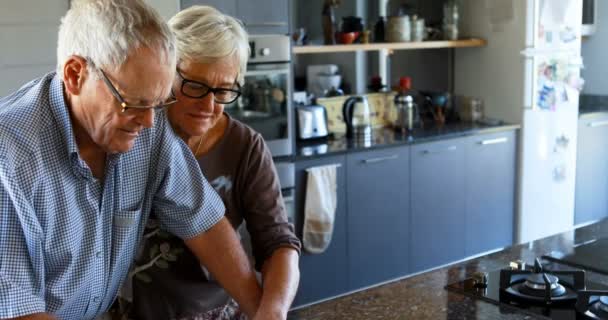 Старшая Пара Взаимодействует Друг Другом Кухне Дома — стоковое видео