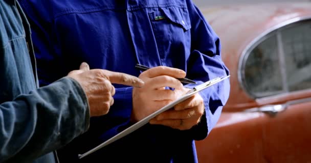 Twee Mechanica Schrijven Klembord Bij Reparatie Garage — Stockvideo