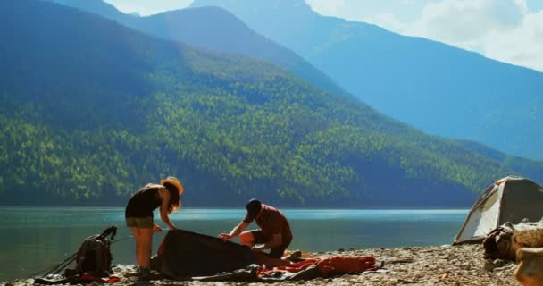 远足夫妇准备帐篷附近的河畔在一个晴朗的日子4K — 图库视频影像