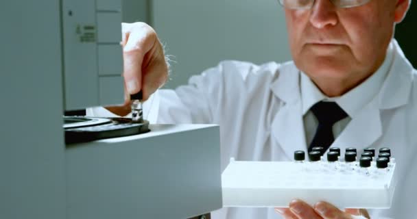 の研究室でマシンにテスト チューブを配置する男性の科学者 — ストック動画