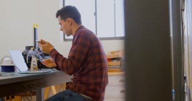 Mekanik atölye 4 k masasında cep telefonu kullanırken bir zincir halkası holding