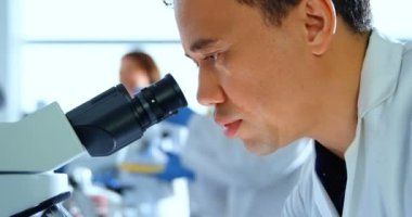 4 k laboratuarda mikroskop kullanarak erkek bilim adamı Close-up