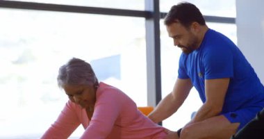 Kadın kıdemli yoga yoga merkezi 4 k gerçekleştirmede yardımcı antrenör