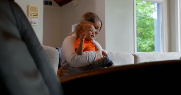 母亲抱着儿子坐在沙发上在家4K — 图库视频影像