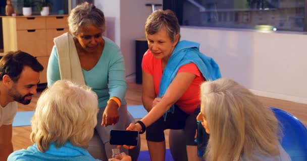 高级妇女在瑜伽中心讨论手机4K — 图库视频影像
