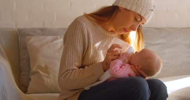母の家の でリビング ルームで彼女の赤ちゃんにミルクを供給 — ストック動画