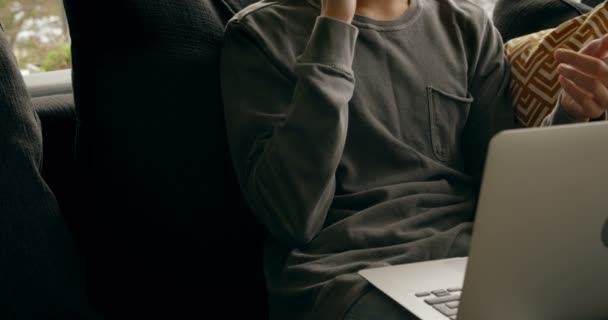 Ung Man Talar Mobiltelefon När Använder Laptop Hemma — Stockvideo