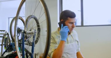 Bisiklet atölyesinde 4 k kısayollarımı cep telefonda konuşan adam