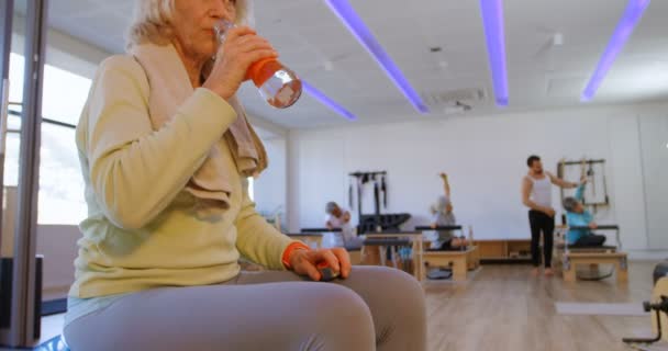 在瑜伽中心的疲惫的高级妇女饮水4K — 图库视频影像