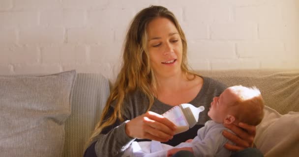 母の家の でリビング ルームで彼女の赤ちゃんにミルクを供給 — ストック動画