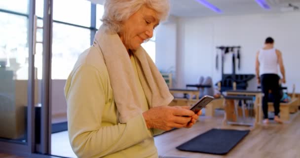 Vista Lateral Mujer Mayor Utilizando Teléfono Móvil Centro Yoga — Vídeos de Stock