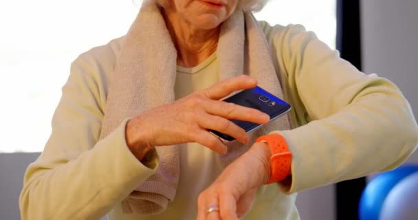 Senior Vrouw Met Behulp Van Mobiele Telefoon Smartwatch Yogacentrum — Stockvideo