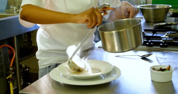 女厨师将用勺子倒汤到厨房4K 的盘子里 — 图库视频影像