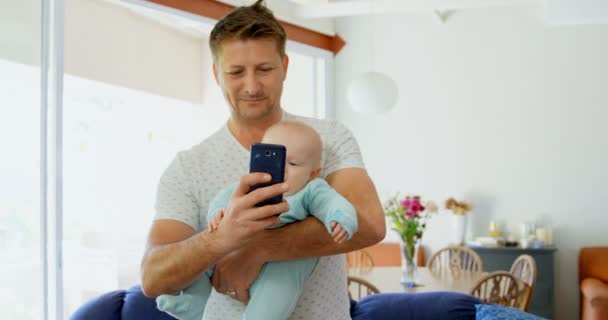 Far Och Baby Pojke Med Hjälp Mobiltelefon Vardagsrummet Hem — Stockvideo