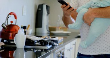 Baba ve bebek çocuk cep telefonuyla mutfakta ev 4 k