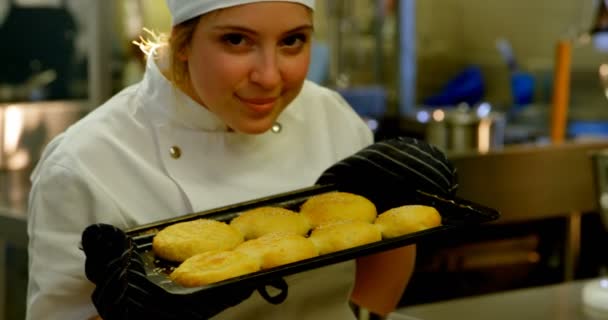 のキッチンでクッキーのトレイを保持している女性シェフの肖像画 — ストック動画
