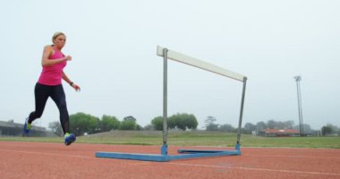 Kadın atlet bir koşu parkuru, spor mekan 4 k üzerinde engellerin atlama