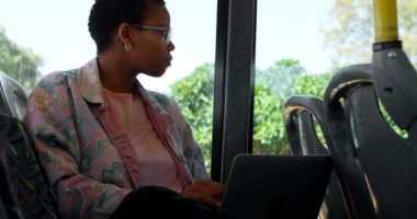 Düşünceli banliyö otobüste dizüstü bilgisayar kullanırken pencereden bakıyor