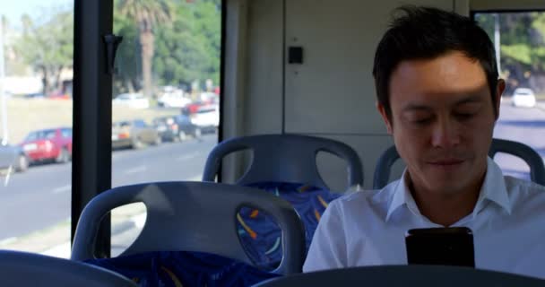 Glücklicher männlicher Pendler mit Handy im Bus 