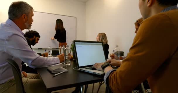 collègues d'affaires interagissant entre eux dans la salle de conférence au bureau 