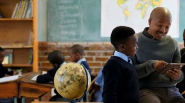 Erkek öğretmen okulda sınıfta öğrencilerle dijital tablet kullanma 