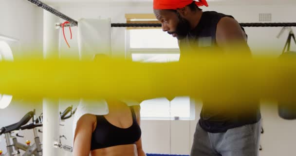 フィットネス スタジオ でボクシングのリングで男性トレーナー トレーニング女性ボクサー — ストック動画